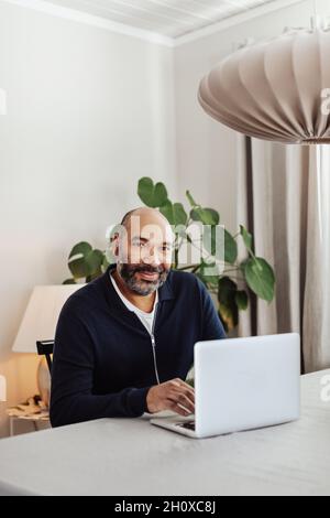 Smiling man using laptop at home Stock Photo