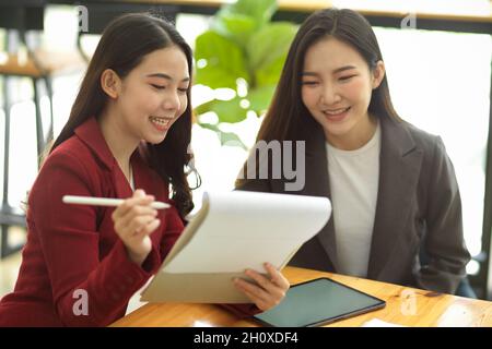 Businesswomen in the office brainstorming and discussing a new marketing strategy to engage with customer. Teamwork and partnership concept. Stock Photo