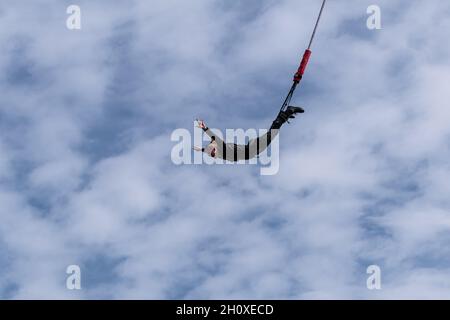 Bungy jumper jumping from a high bridge over the void and down to the deep north sea Stock Photo