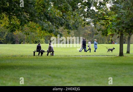 London, England, UK. Regent's Park: two women talking on a bench, people walking past Stock Photo