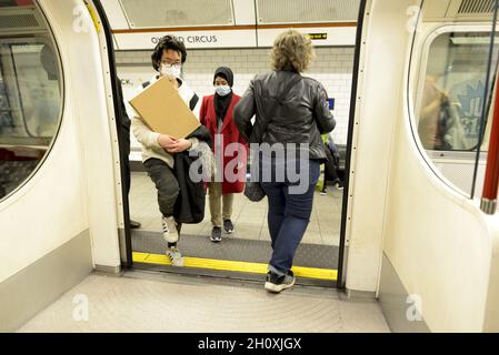 London, England, UK. London underground: people in COVID masks getting on a train at Oxford Circus Stock Photo