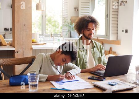 Father using laptop with son drawing at home Stock Photo