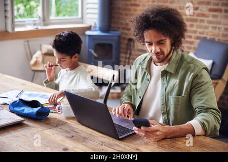 Father using laptop with son doing homework Stock Photo