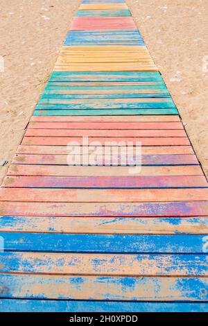Beach path to the sea made of multi-colored painted wooden planks on the sand Stock Photo