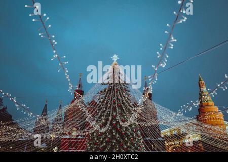 Christmas tree in Red Square Moscow decorated with gold balls, star, garlands, twinkling lights. Garlands of golden lights spread out from the top of Stock Photo