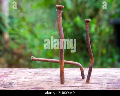 Macro photography of three rusted and bent nails nailed to a wooden plank, captured in a farm near the town of Arcacuco in central colombia. Stock Photo