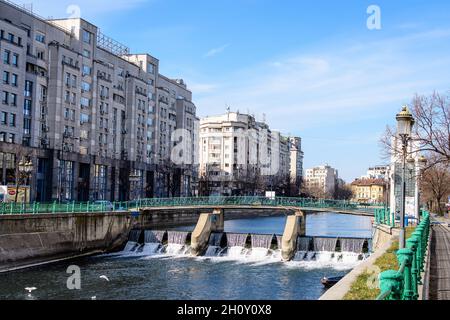 Bucharest, Romania, 13 February 2021 - Small bridge, old buildings near Dambovita river and clear blue sky in the center of Bucharest, Romania, in a s Stock Photo