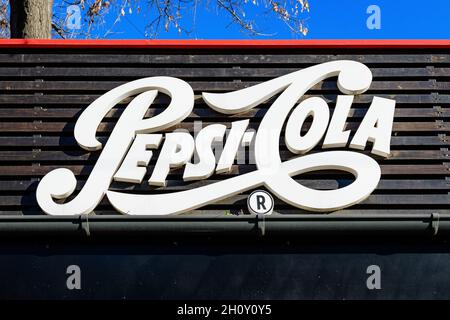 Bucharest, Romania, 1 January 2021 - Old vintage white logo of Pepsi Cola drink displayed on a dark background at a restaurant in a sunny winter day Stock Photo