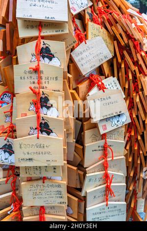 tokyo, japan - november 23 2019: Heap of hung wooden shinto Ema plaques depicting the guardian spirit Sugawara no Michizane dedicated to success Stock Photo