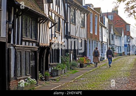 Rear view of two women walking along cobbled lane past half timbered medieval houses in town of Rye East Sussex England Great Britain UK KATHY DEWITT Stock Photo