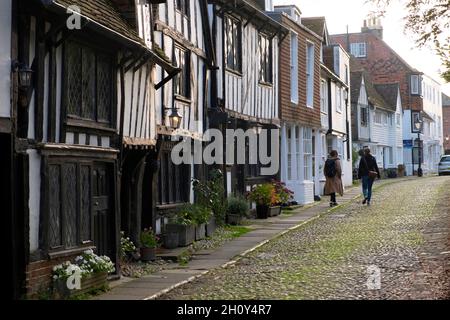 Rear view of two women walking along cobbled lane past half timbered medieval houses in town of Rye East Sussex England Great Britain UK KATHY DEWITT Stock Photo