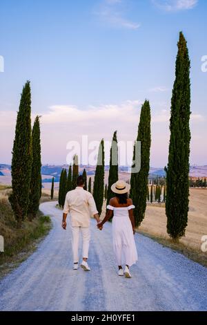 Tuscany Italy, Perfect Road Avenue through cypress trees ideal Tuscan landscape Italy, couple man and woman on vacation in Toscane Stock Photo