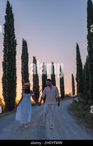 Tuscany Italy, Perfect Road Avenue through cypress trees ideal Tuscan landscape Italy, couple man and woman on vacation in Toscane Stock Photo