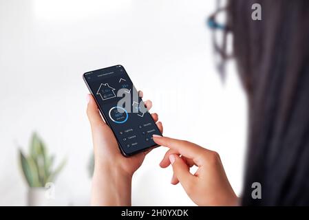 Smart home app concept on smart phone in woman hands. Home interior in background Stock Photo