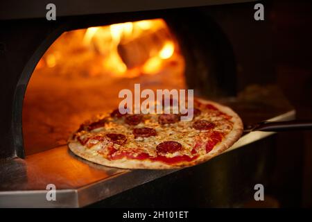 Close Up Of Pepperoni Pizza Being Baked In Wood Fired Oven Stock Photo
