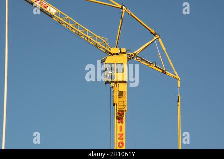 A yellow tower crane at work in Glasgow against a clear blue sky background Stock Photo
