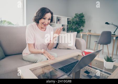 Photo portrait senior woman sitting on sofa working talking on web camera online on computer at home Stock Photo