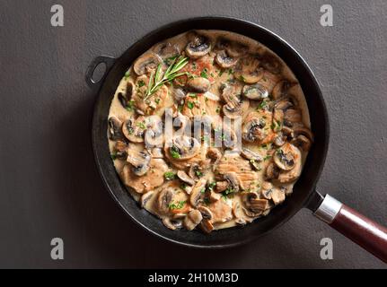 Pork medallions with mushroom gravy in cast iron pan over dark stone background. Top view, flat lay Stock Photo