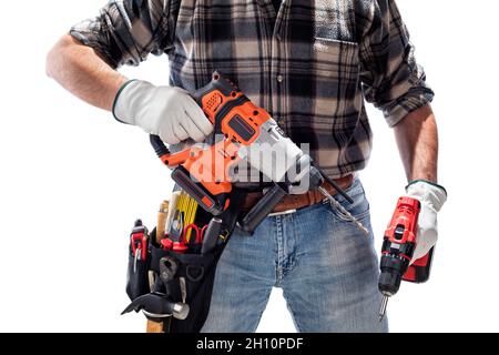 Carpenter worker at work holding the rechargeable hammer drill and the rechargeable screwdriver, isolated on white background. Construction industry. Stock Photo
