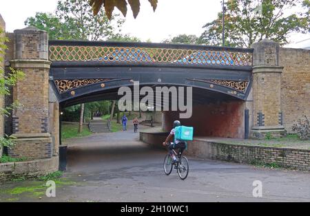 Peckham, south London, UK. A cyclist passes under a Victorian bridge on the old Surrey Canal route which is now a landscaped path and cycle route Stock Photo