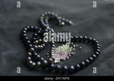 Strings of pearls and silver skulls on leather background Stock Photo