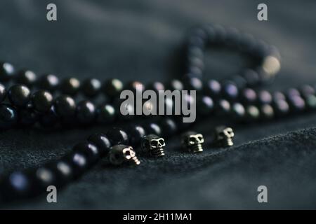 Strings of pearls and silver skulls on leather background Stock Photo