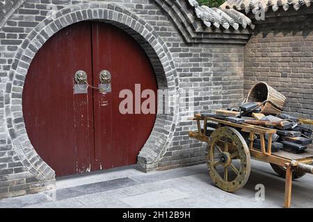 Maroon painted-round door-wooden cart-building materials. City Wall's Yongning South Gate-Xi'an-China-1589 Stock Photo