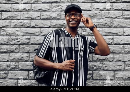 African american man wearing glasses for vision, against black brick wall background Stock Photo