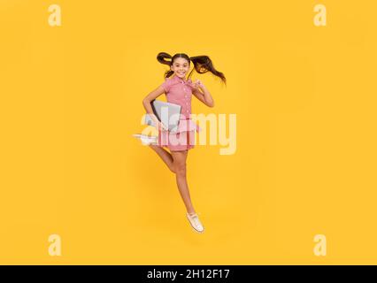 happy child girl hurry up running hold notebook to find sale and discount, energy Stock Photo