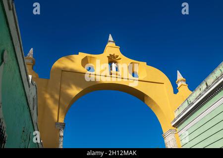 Sunlit colonial arch 'Arc de San Juan' with shadows of a palm tree in the historic center of Merida, Mexico Stock Photo