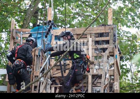 Aylesbury Vale, UK. On day six of the Anti HS2 protester eviction, National Eviction Team Enforcement Agent climbers were attempting to dismantle a huge protester tower built from pallets and scrap metal by the protesters. Dan Hooper nicknamed Swampy, is one of the activists in underground tunnels underneath the tower. HS2 were again causing huge traffic jams on the A413 due to their temporary traffic lights. The HS2 High Speed Rail construction work is destroying huge areas of woodland and wildlife habitats across the Chilterns. Credit: Maureen McLean/Alamy Live News Stock Photo