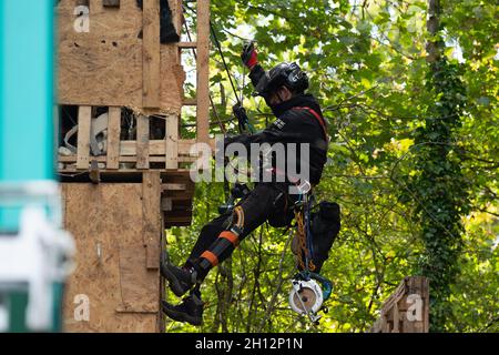 Aylesbury Vale, UK. On day six of the Anti HS2 protester eviction, National Eviction Team Enforcement Agent climbers were attempting to dismantle a huge protester tower built from pallets and scrap metal by the protesters. Dan Hooper nicknamed Swampy, is one of the activists in underground tunnels underneath the tower. HS2 were again causing huge traffic jams on the A413 due to their temporary traffic lights. The HS2 High Speed Rail construction work is destroying huge areas of woodland and wildlife habitats across the Chilterns. Credit: Maureen McLean/Alamy Live News Stock Photo