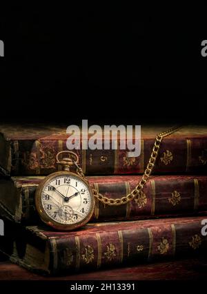 Vintage Antique pocket watch and old books on black background Stock Photo