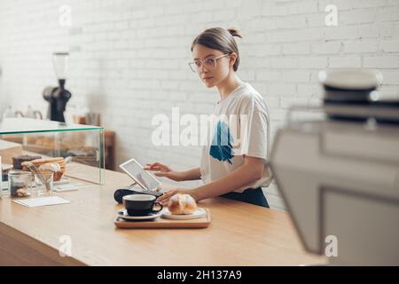 Beautiful young woman working in coffee shop Stock Photo