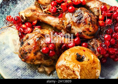 Roasted chicken legs with berries.Chicken drumsticks with viburnum.Close up Stock Photo