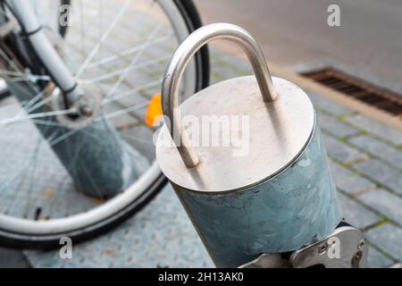 Close - up on a bicycle rack made of metal. Brick pavement and bicycle wheel in the background. Stock Photo