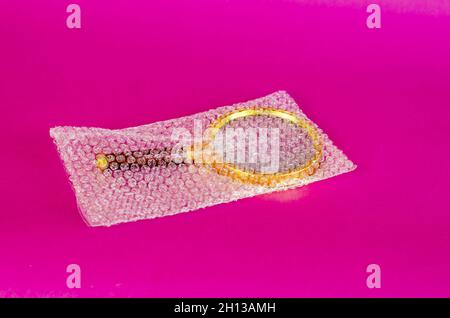 Magnifying glass and bubble wrap on pink background. Selective Focus. Stock Photo