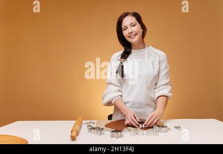Young woman pastry chef in white apron prepares gingerbread. Stock Photo