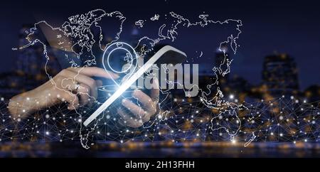 Concept on business, politics, ecology and media. Hand touch white tablet with digital hologram world, earth, map, Location Marker sign on city dark b Stock Photo