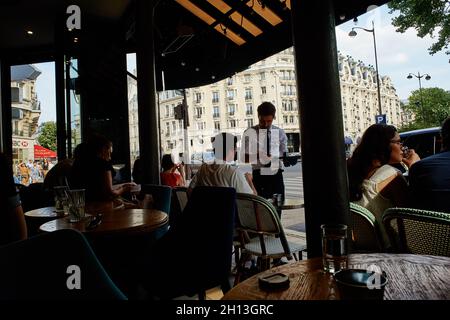 Paris, France - July 2019: local people walking along the terrace of the Sip Babylone bar, just facing the hotel Lutecia at  the Sèvres-Babylone metro