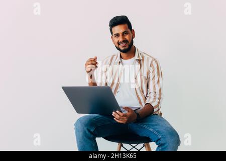 Portrait of business Indian man using laptop computer, looking side and smiling, standing isolated on white background Stock Photo