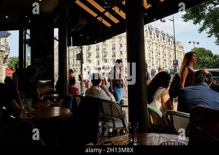 Paris, France - July 2019: local people walking along the terrace of the Sip Babylone bar, just facing the hotel Lutecia at  the Sèvres-Babylone metro