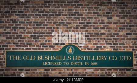 Bushmills, Northern Ireland, Aug 2019 The Old Bushmills Distillery Co. Ltd Licensed to distil in 1608 sign on rustic brick wall Stock Photo