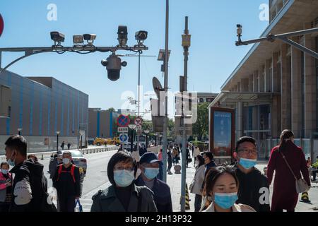 Pedestrians walk below CCTV cameras in Wangfujing Street in Beijing, China. 16-Oct-2021 Stock Photo