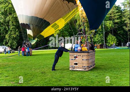 Vilnius, Lithuania - September 14, 2021: Ground staff man holding the basket with pilot and passengers inside before the launch of hot air balloons at Stock Photo