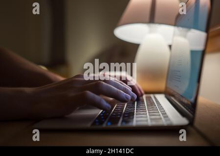 Writer typing modern computer keyboard writing novel in the evening house muffled light. Distance or freelance work or home office on worldwide quaran Stock Photo