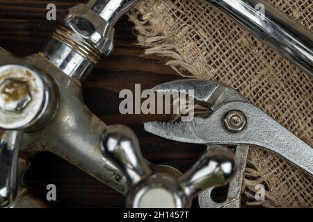 A wrench and an old bathroom faucet on a wooden table Stock Photo