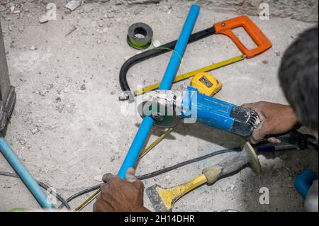 Plumber using electric saw cutting pvc pipe during bathroom renovation Stock Photo