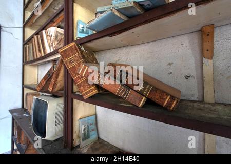 Old books on a shelf of an abandoned dental office in Northern Italy. Urbex in Italy Stock Photo