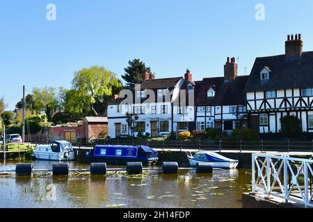 Attractive properties overlooking the River Avon as it passes through Tewkesbury.Pleasure boats at moorings on quayside. Barrier for nearby mill weir. Stock Photo